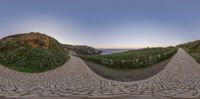 the camera panoramic view of an empty path leading to a beach at dusk