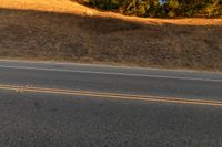 an orange motorcycle riding along the middle of an empty road in the country side road