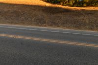 an orange motorcycle riding along the middle of an empty road in the country side road