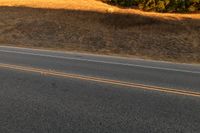 an orange motorcycle riding along the middle of an empty road in the country side road