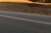 an orange motorcycle riding along the middle of an empty road in the country side road