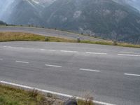 a motorcycle is sitting at the edge of a curve and mountains are in the background