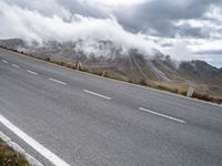 a car that is standing on a road in a mountainous area with fog and clouds