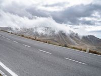 a car that is standing on a road in a mountainous area with fog and clouds