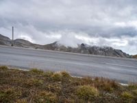 clouds hovering over mountains near road on cloudy day on highway below, near grassy area with a fire hydrant