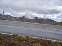 clouds hovering over mountains near road on cloudy day on highway below, near grassy area with a fire hydrant