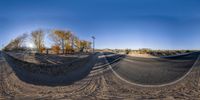 a 360 - view camera is positioned in the foreground to the image and shows two tracks of dirt and trees