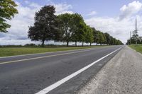 a country road with two lanes and one tree line down it's left side