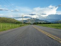 a lone country road is in the countryside area with mountains on both sides and barbed fence between the two sides