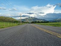 a lone country road is in the countryside area with mountains on both sides and barbed fence between the two sides