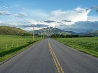 a lone country road is in the countryside area with mountains on both sides and barbed fence between the two sides