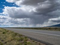 there is a man that is walking on the road looking at something interesting with a cloudy sky and a bright blue sign