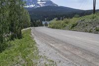 a winding rural road leading to a mountain top with a mountain peak in the distance