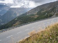 a man rides his motorcycle on a winding road above the mountains in italy on a cloudy day