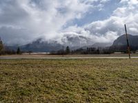 a grassy field with an empty road going through it and some mountains in the distance