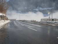 a snowy mountain sits above a empty road with signs on either side of it, near a large highway