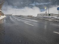 a snowy mountain sits above a empty road with signs on either side of it, near a large highway