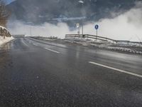a snowy mountain sits above a empty road with signs on either side of it, near a large highway