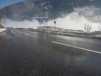 a snowy mountain sits above a empty road with signs on either side of it, near a large highway