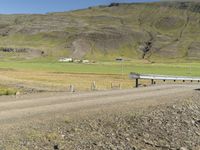 a car traveling down a dirt road near mountains and fields covered in sheep grazing on the side