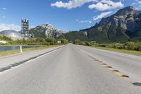 a highway with a road sign and some mountains in the background on an empty road