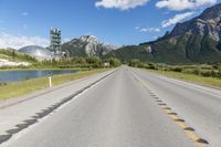 a highway with a road sign and some mountains in the background on an empty road