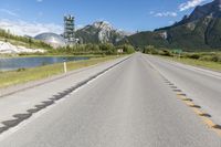 a highway with a road sign and some mountains in the background on an empty road