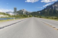 a highway with a road sign and some mountains in the background on an empty road