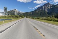 a highway with a road sign and some mountains in the background on an empty road