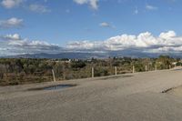 a view of a barren landscape with mountains in the background and clouds overhead with the area's vegetation