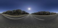 a view of a road through a fisheye lens on an asphalt road with trees and the sun above it