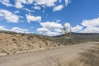 a dirt road and blue sky in the mountains in the desert with trees on the side
