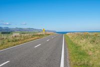 empty road with signs on the sides of both sides and a blue ocean in the back ground