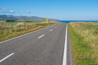 empty road with signs on the sides of both sides and a blue ocean in the back ground