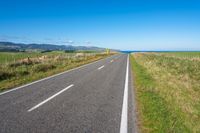 empty road with signs on the sides of both sides and a blue ocean in the back ground