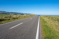 empty road with signs on the sides of both sides and a blue ocean in the back ground