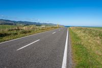 empty road with signs on the sides of both sides and a blue ocean in the back ground