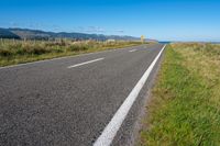 empty road with signs on the sides of both sides and a blue ocean in the back ground