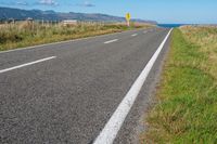 empty road with signs on the sides of both sides and a blue ocean in the back ground