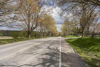 there is a small empty road with trees and grass on both sides of the street