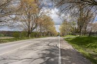 there is a small empty road with trees and grass on both sides of the street