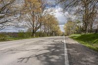 there is a small empty road with trees and grass on both sides of the street