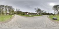 a panoramic view of a rural road surrounded by trees and lawns with homes