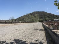 a view from a bridge overlooking trees and a mountain range of hills behind a bridge