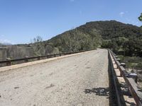 a view from a bridge overlooking trees and a mountain range of hills behind a bridge