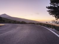 a road and mountain at sunset with a person on the side taking a photo of it