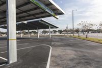 a parking lot with a parked car under a covered shelter and green grass around it