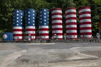 a row of colorful cylinders with stars and stripes in them, sitting on a paved surface