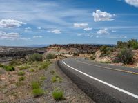 there is a scenic highway winding through the desert landscape with the cloudy sky above it