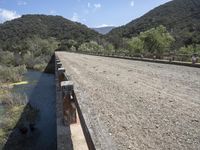 a view from a bridge overlooking trees and a mountain range of hills behind a bridge